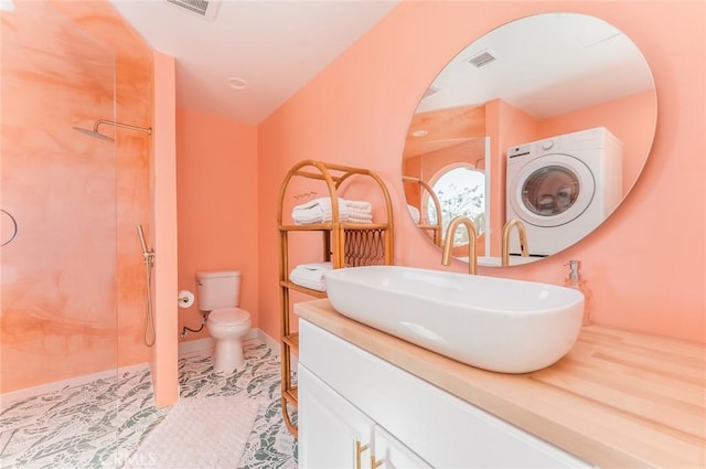 bathroom featuring vanity, a shower, tile patterned flooring, washer / dryer, and toilet