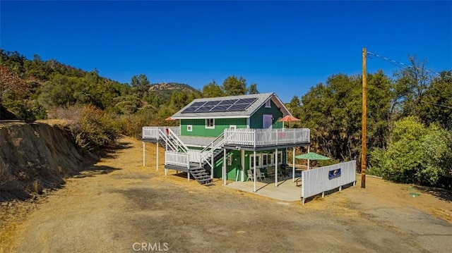 back of property featuring solar panels and a wooden deck