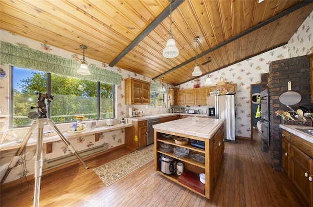 kitchen with tile counters, hanging light fixtures, stainless steel appliances, wood-type flooring, and vaulted ceiling