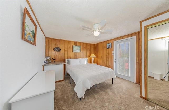 bedroom featuring carpet, access to outside, ceiling fan, and wooden walls