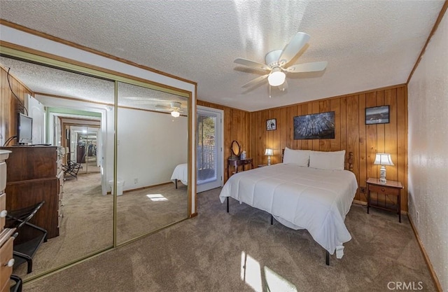 bedroom with a textured ceiling, ceiling fan, wooden walls, carpet floors, and a closet