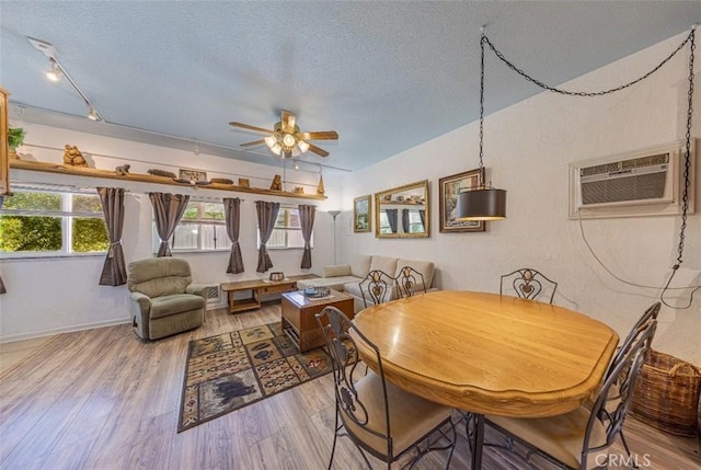 dining area with track lighting, an AC wall unit, ceiling fan, a textured ceiling, and wood-type flooring