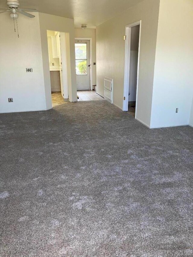 empty room featuring ceiling fan and light carpet