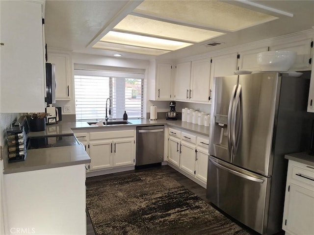 kitchen featuring sink, dark wood-type flooring, stainless steel appliances, a raised ceiling, and white cabinets