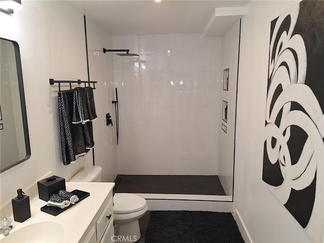 bathroom featuring vanity, toilet, and tiled shower