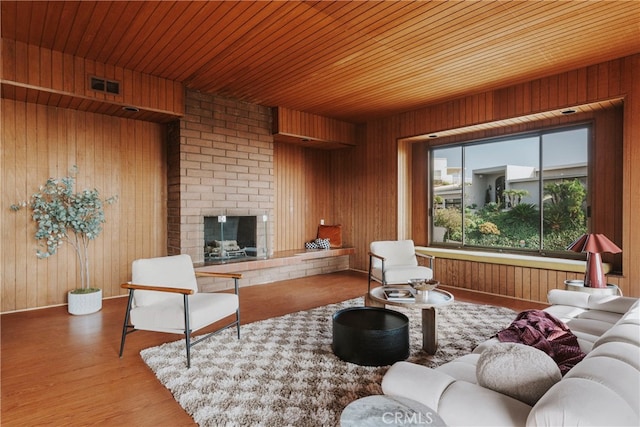 living room featuring wood ceiling, wood-type flooring, a fireplace, and wooden walls