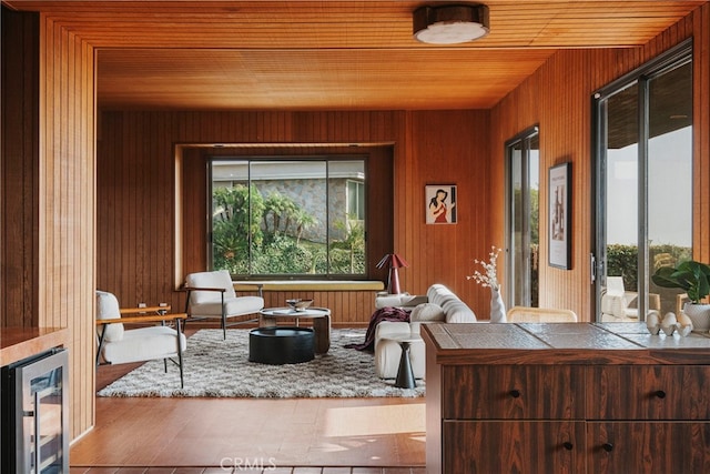 sitting room featuring wood walls, wooden ceiling, and wine cooler