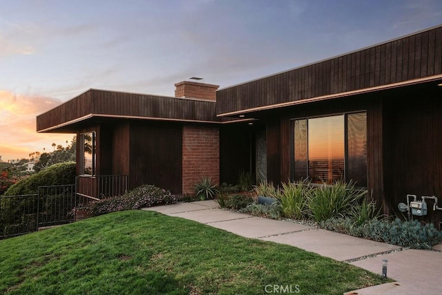 exterior entry at dusk featuring a lawn