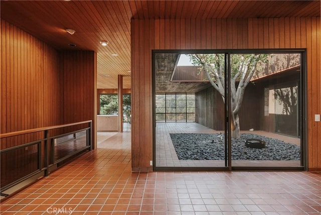 doorway to outside with tile patterned flooring, wood walls, and wooden ceiling