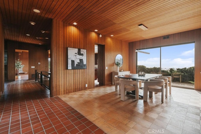 dining area featuring wooden ceiling and wooden walls