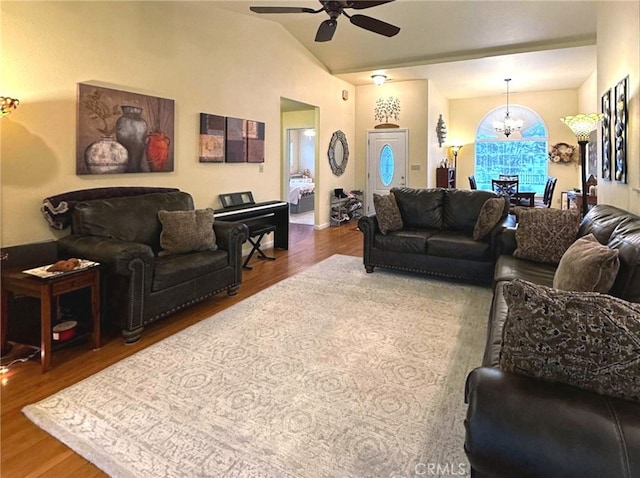 living room with hardwood / wood-style floors, ceiling fan with notable chandelier, and vaulted ceiling