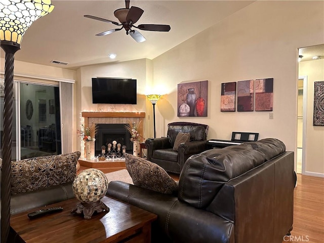 living room featuring a brick fireplace, ceiling fan, and light hardwood / wood-style flooring