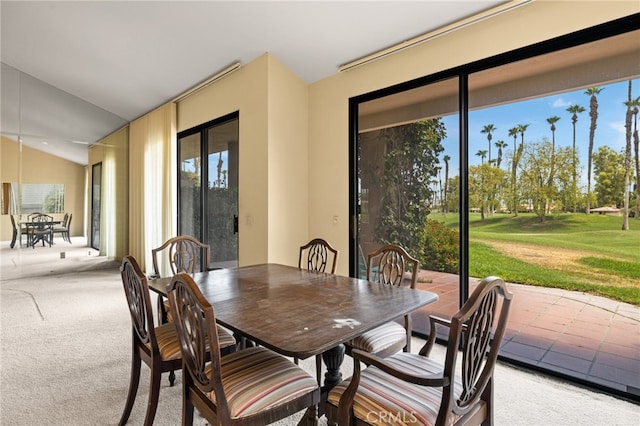 carpeted dining area featuring vaulted ceiling