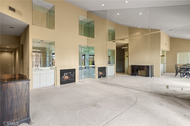 living room featuring a high ceiling, light colored carpet, and sink