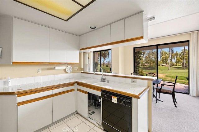 kitchen with tile counters, dishwasher, white cabinets, and kitchen peninsula