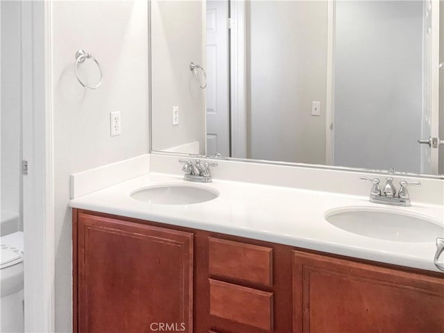 full bathroom with toilet, double vanity, and a sink