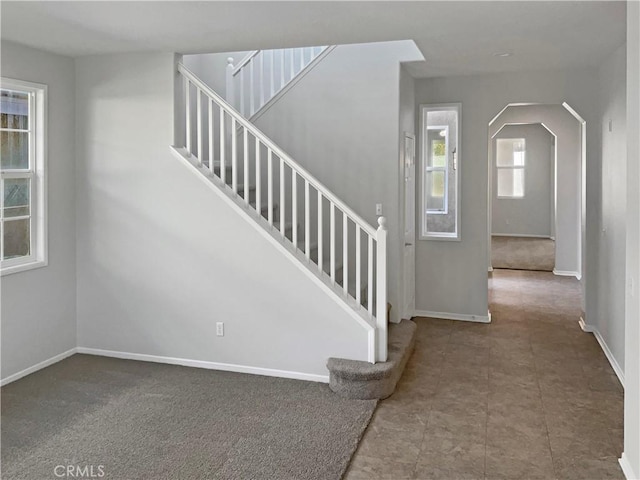 stairs with arched walkways and baseboards