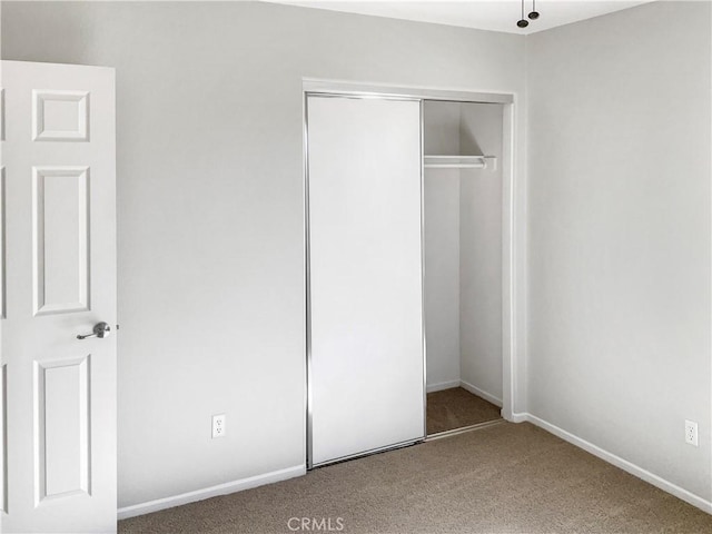 unfurnished bedroom with carpet floors, baseboards, and a closet