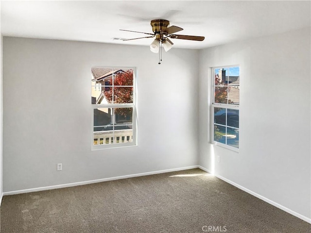 carpeted spare room with a wealth of natural light and ceiling fan