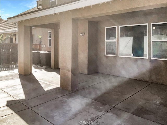 doorway to property with a patio area, fence, and stucco siding