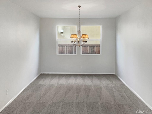 carpeted spare room featuring baseboards and an inviting chandelier