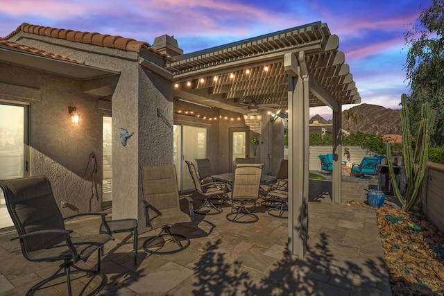 patio terrace at dusk featuring a mountain view and a pergola