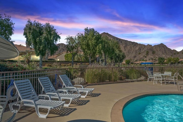 pool at dusk with a patio area and a mountain view