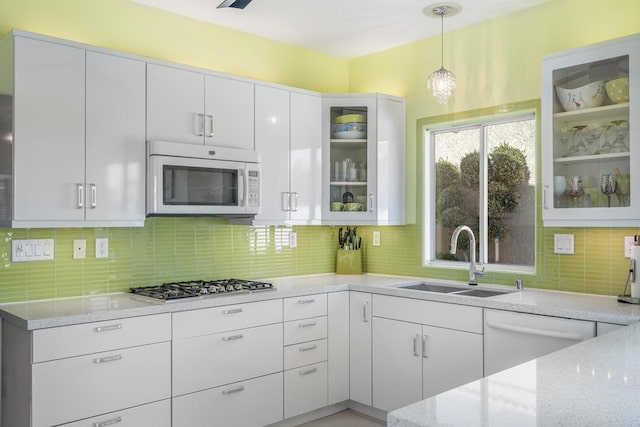 kitchen featuring white cabinetry, sink, tasteful backsplash, decorative light fixtures, and white appliances