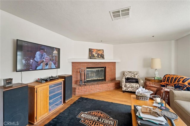 living room with a fireplace, a textured ceiling, and light hardwood / wood-style floors