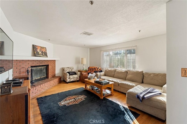 living room with hardwood / wood-style floors, a fireplace, and a textured ceiling