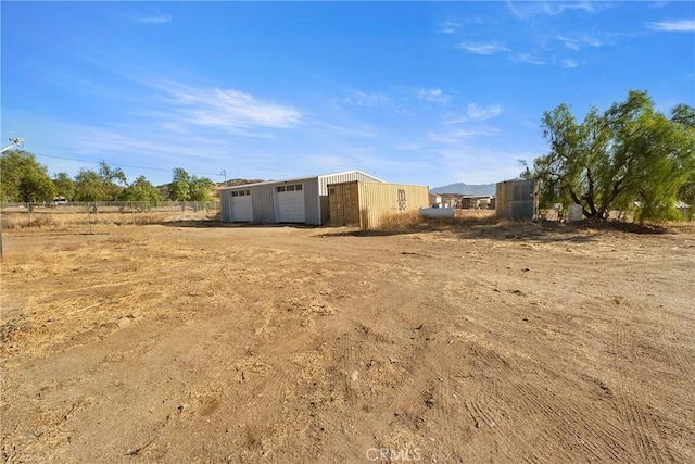 view of yard featuring a rural view, an outdoor structure, and a garage