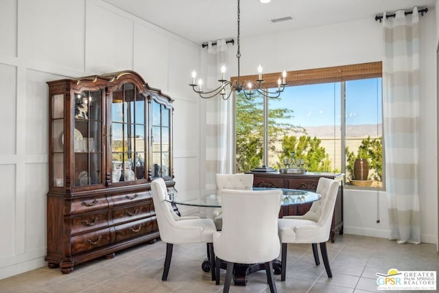 dining room featuring a mountain view, light tile patterned floors, a healthy amount of sunlight, and an inviting chandelier