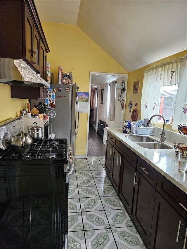 kitchen featuring a sink, range with gas stovetop, lofted ceiling, light countertops, and under cabinet range hood