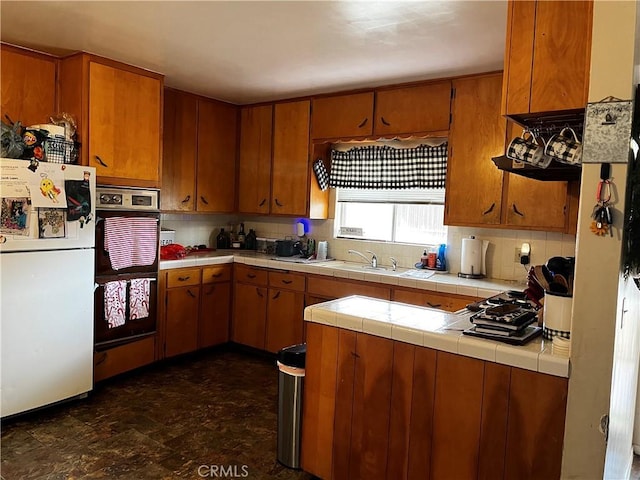 kitchen with sink, double oven, tasteful backsplash, tile counters, and white fridge