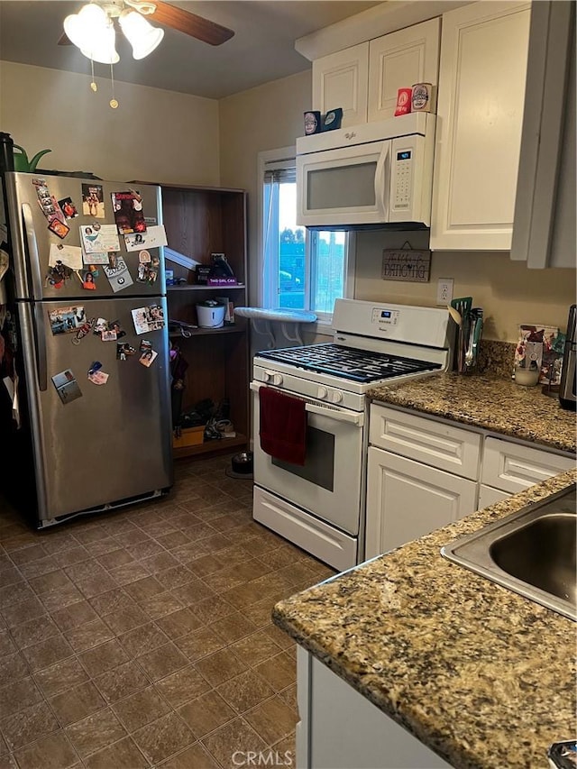 kitchen featuring white appliances, sink, ceiling fan, stone countertops, and white cabinetry