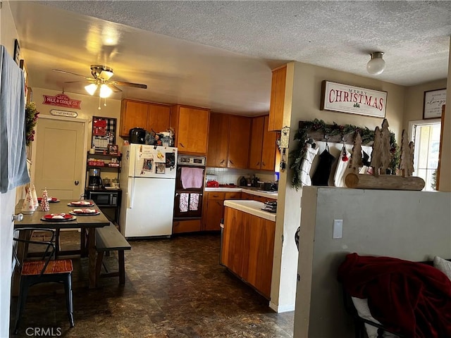 kitchen featuring a textured ceiling, white fridge, oven, and ceiling fan