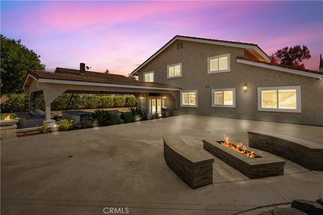 view of front of home featuring stucco siding, concrete driveway, a fire pit, and a patio