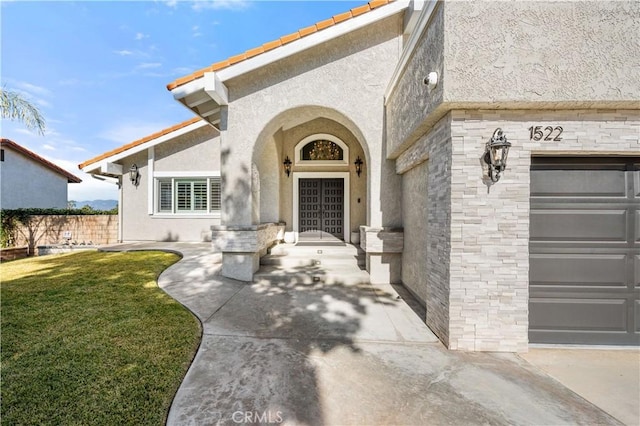 doorway to property featuring stucco siding, an attached garage, and a lawn