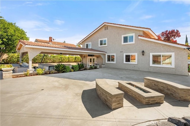 rear view of house featuring an outdoor fire pit and a patio