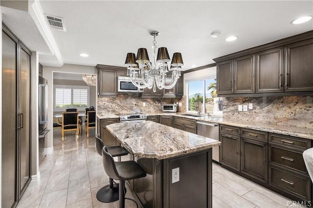 kitchen with visible vents, a center island, stainless steel appliances, an inviting chandelier, and dark brown cabinets