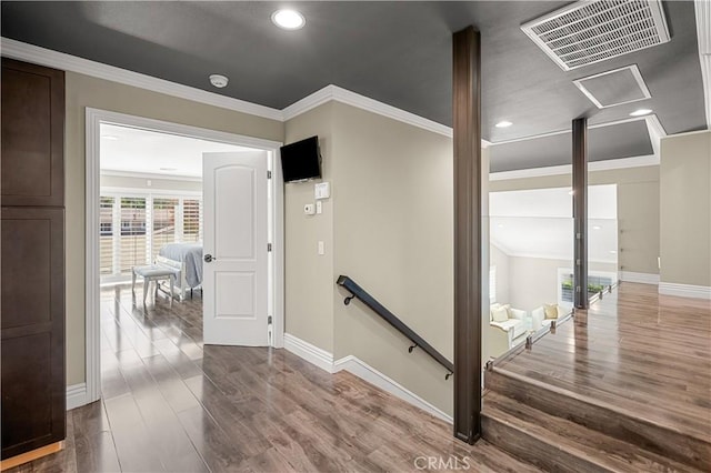 hallway featuring visible vents, an upstairs landing, dark wood-type flooring, crown molding, and baseboards