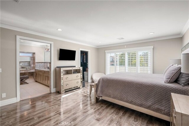 bedroom featuring ensuite bathroom, light hardwood / wood-style flooring, and crown molding