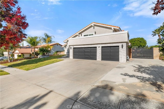 view of front of property featuring stucco siding, a gate, concrete driveway, an attached garage, and a front yard