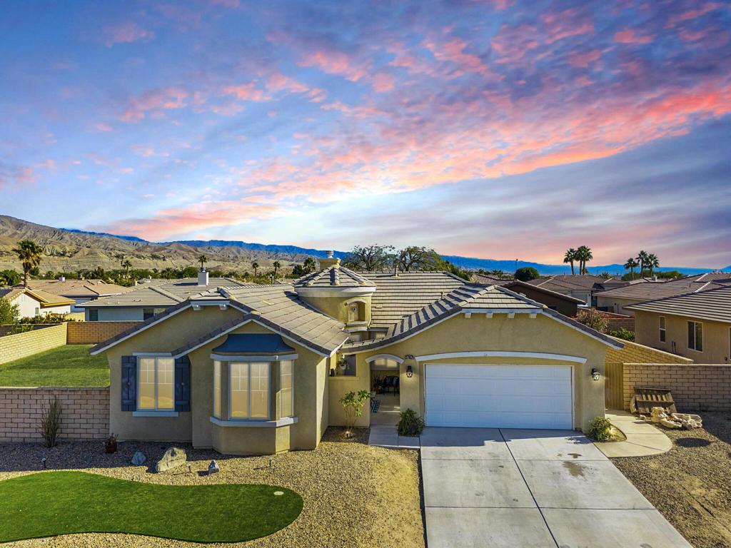 ranch-style home with a mountain view, a garage, and a lawn