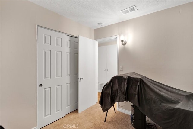 bedroom featuring light carpet, a closet, and a textured ceiling