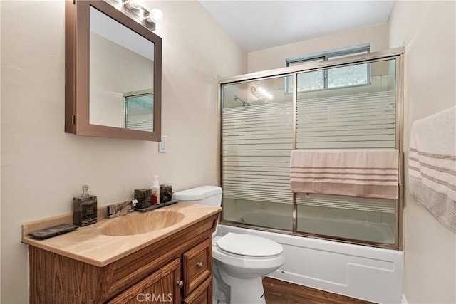 full bathroom with hardwood / wood-style floors, vanity, toilet, and enclosed tub / shower combo