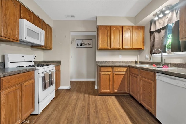 kitchen featuring hardwood / wood-style floors, white appliances, and sink