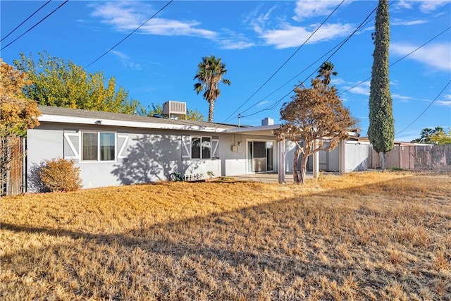 back of property featuring a lawn and central air condition unit