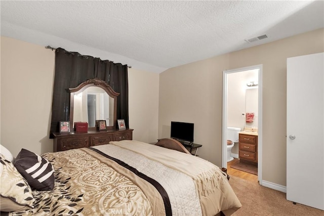 carpeted bedroom featuring a textured ceiling and connected bathroom