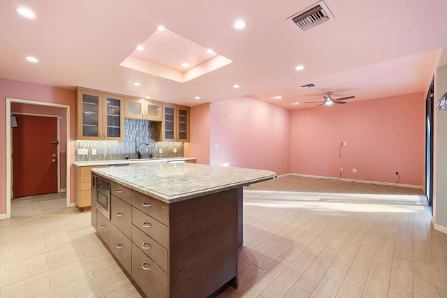 kitchen with tasteful backsplash, ceiling fan, light hardwood / wood-style flooring, and a kitchen island